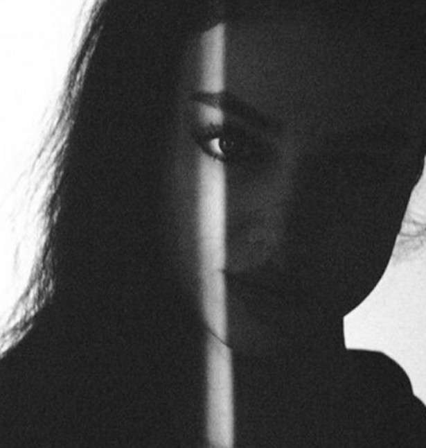 Black and white portrait of a woman in deep shadow, with a narrow strip of light falling down her face