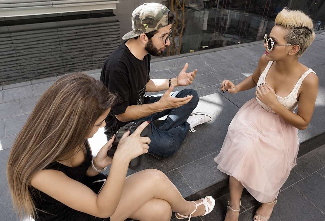 An outdoor coaching session: a coach talks with a model while a woman checks a camera